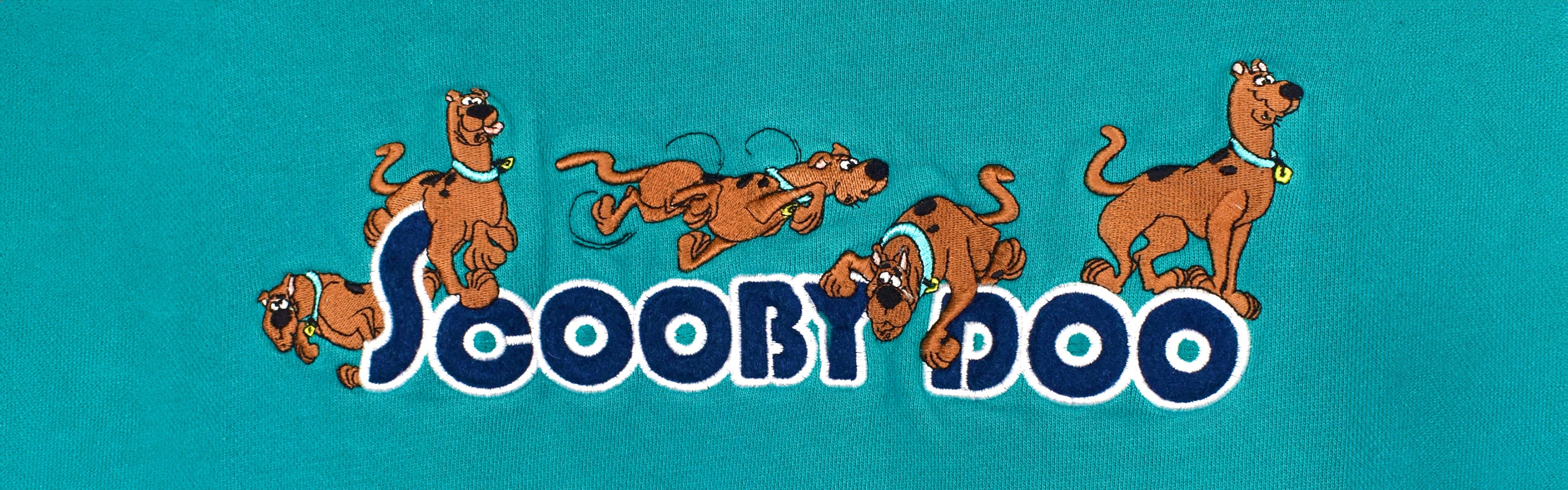Close-up of a blue vintage sweatshirt with detailed embroidery of Scooby-Doo as the focal point.